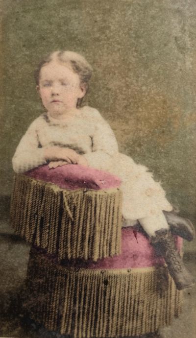Restored and colorized (AI-assisted); faces are the original photo, colours are a best guess. Mary Martin at five years old — carte de visite, G. C. Rhine, Gallatin, Tennessee.