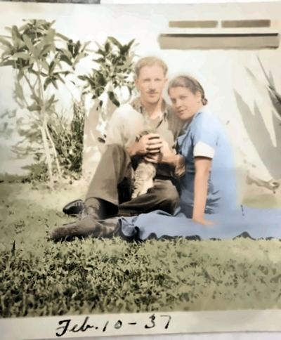 Enhanced (AI-assisted, non-generative): glare reduced, cleaned and upscaled. William Harry Proeger and Aileane (Da Silva) Proeger on the grass with a cat, 10 February 1937 — from the Patricia Collins collection