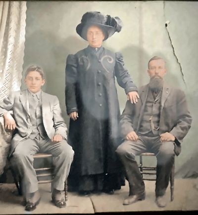 Enhanced (AI-assisted, non-generative): glare reduced, cleaned and upscaled. Frank Silva Jr, his mother Anna L. Silva and his father Frank Silva Sr — studio portrait, c. 1908–1912 (Patricia Collins's print)